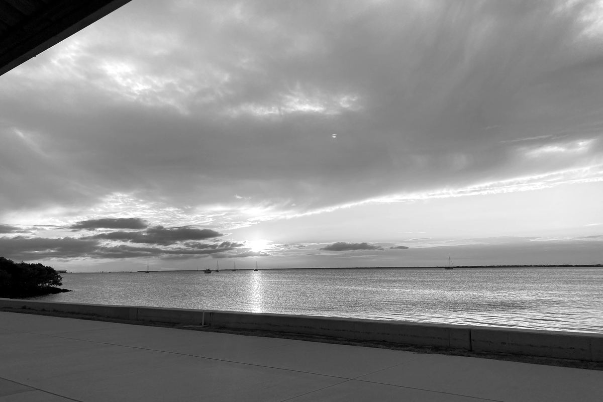A concrete seawall and walkway along Charlotte Harbor at Gilchrist Park in Punta Gorda at sunset
